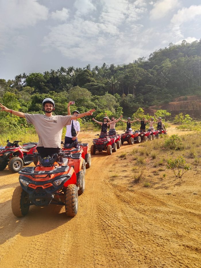 Line of ATV quads on a red-dirt mountain track, Koh Phangan